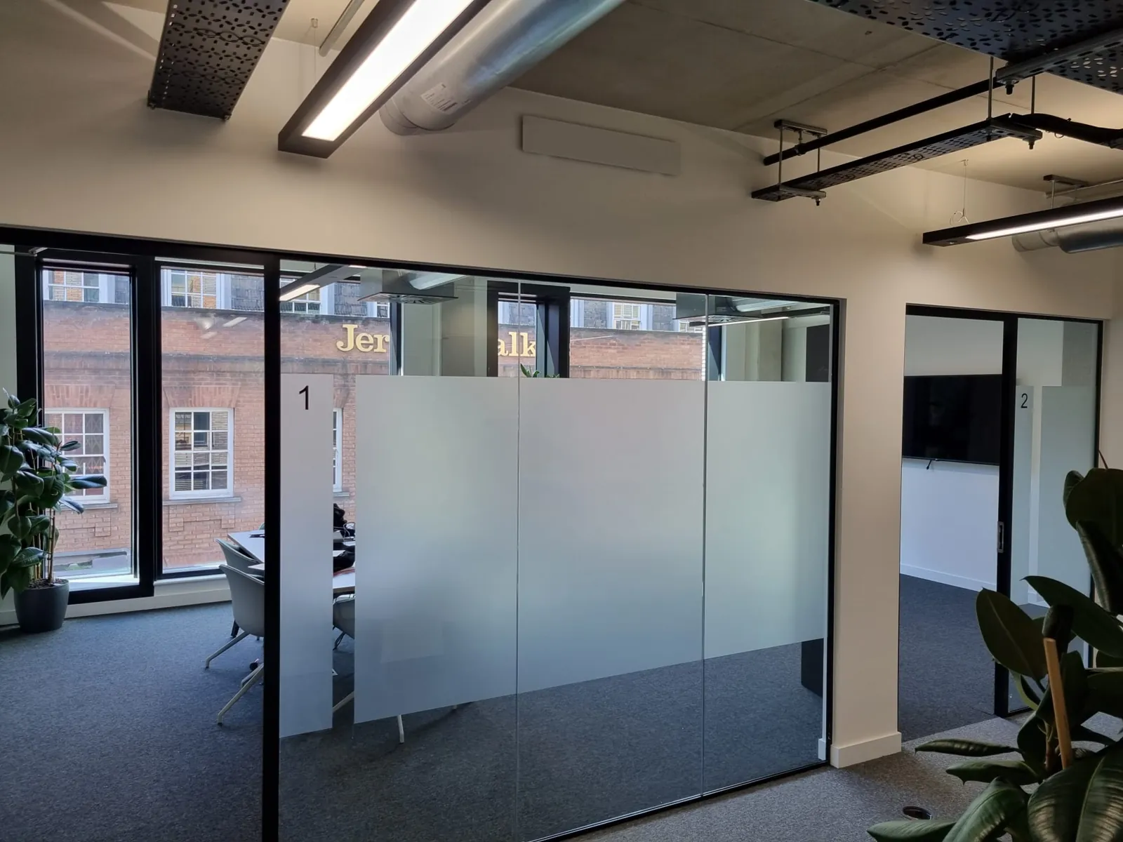 Glazed office partitioning with frosted manifestation bands and a timber door